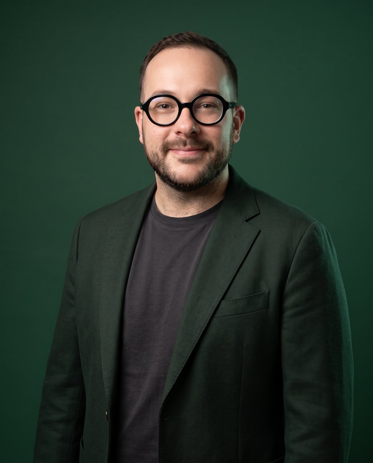 Sergi Passos in a forest-green jacket and black glasses